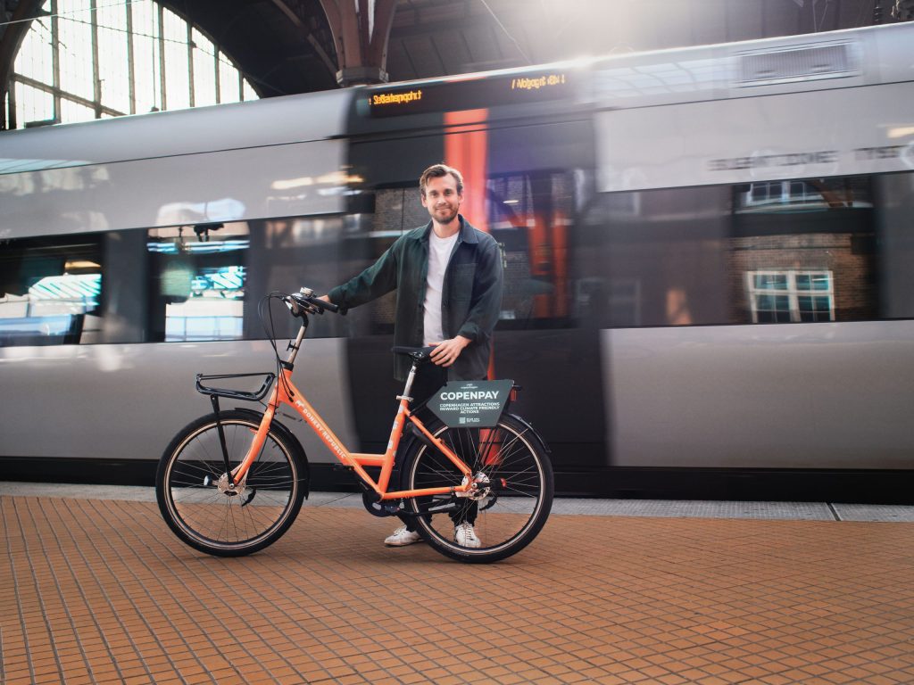 Man in front of a train in Copenhagen, with a bike