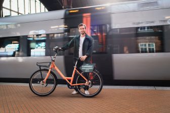 Man in front of a train in Copenhagen, with a bike