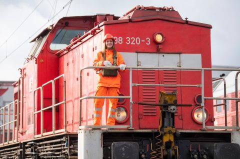 Woman rail worker in front of a locomotive