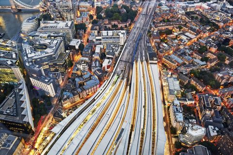 Aerial view of train tracks entering London Bridge illuminated at dusk